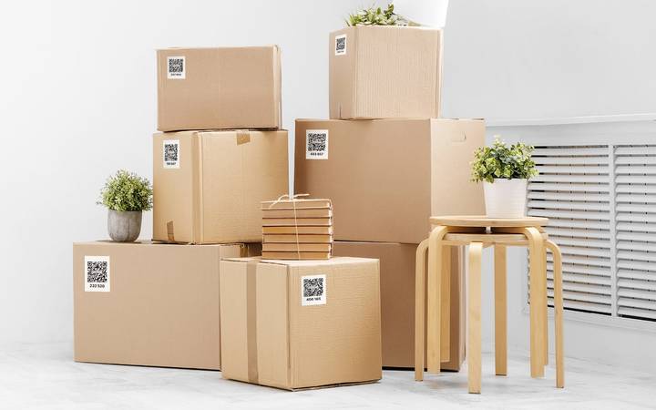Stacked cardboard moving boxes, each with a QR code label on its side