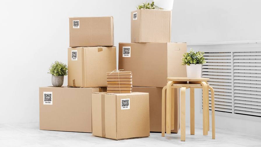 Stacked cardboard moving boxes, each with a QR code label on its side