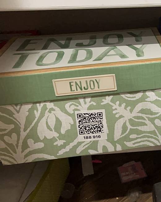 A patterned storage box on a closet shelf with a SmartPacks QR label on its side