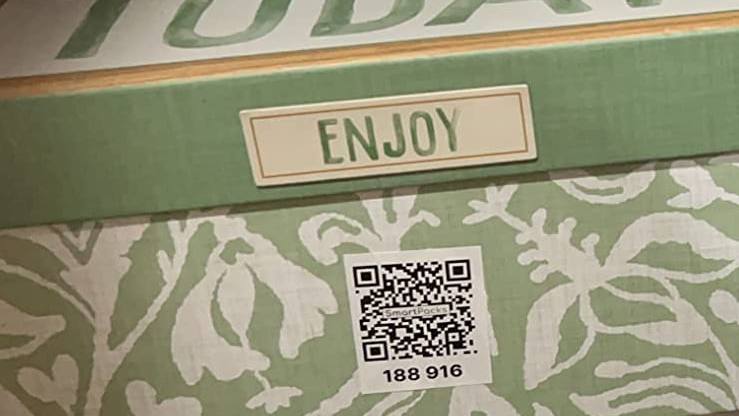 A patterned storage box on a closet shelf with a SmartPacks QR label on its side