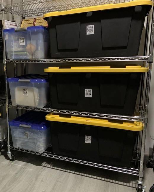Metal shelving with black and clear storage bins, every bin carrying a SmartPacks QR label